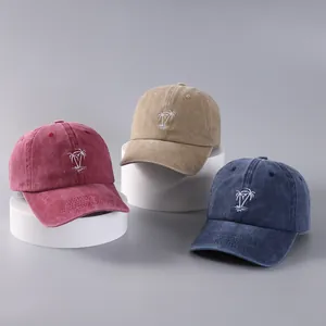 Three embroidered palm tree baseball caps in burgundy, khaki, and navy on white pedestals