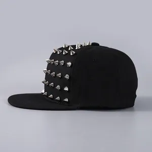 Detail view of five rows of silver punk cone studs on a black canvas hip hop flat bill cap