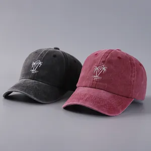 Detail of embroidered coconut tree on vintage washed cotton baseball caps in grey and red