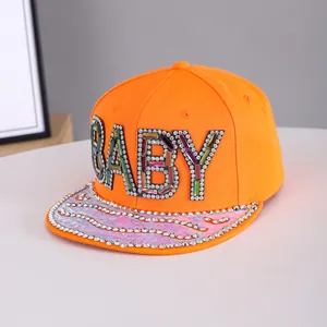 Detail of baby rhinestone lettering on orange hip hop cap with holographic pink brim