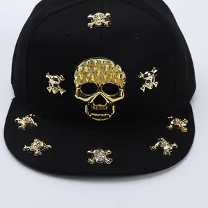 Detailed front view of black flat brim hip hop hat with golden metal skulls and rhinestones