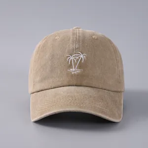 Close-up of a khaki cotton baseball cap with white embroidered palm tree and washed texture