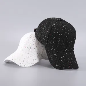 Close-up of black and white tweed baseball caps with shiny sequins and woven texture
