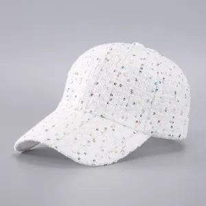 Close-up of white tweed baseball cap with colorful sequins and textured fabric detail