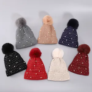 Detail der Winter-Strickmützen mit Perlen, Steinchen und flauschigem Kunstpelz-Bommel