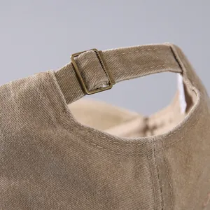 Detailed close-up of brown cotton baseball cap with adjustable brass metal buckle