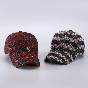 Close-up of baseball caps in red and pink tweed fabric with metallic gold thread detail