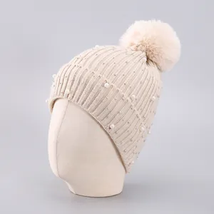 Beigefarbene Strickmütze mit Kunstperlen, Strasssteinen und einem großen flauschigen Bommel