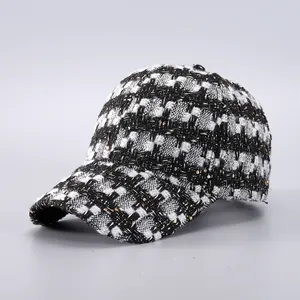 Detail of black and white houndstooth baseball cap with woven gold sequins and tweed texture