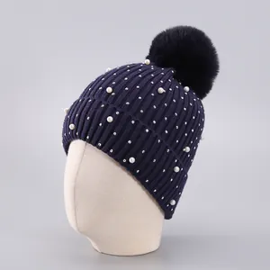 Detail der dunkelblauen Winter-Strickmütze mit Kunstpelz-Bommel und Perlenverzierung