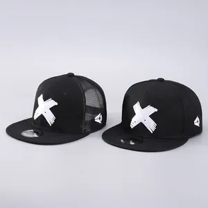 Detail view of black snapback caps featuring white X embroidery and mesh trucker style