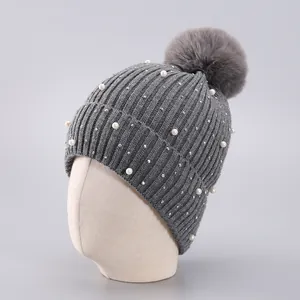 Detail der grauen Strickmütze mit Bommel, eleganten Perlen und glänzenden Kristallen