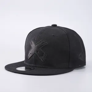 Close-up of black snapback hat featuring 3D embroidered X logo and twill texture detail