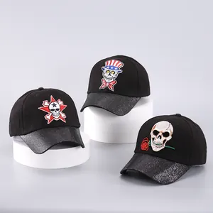 Detalle de gorras de béisbol negras con bordado de calaveras y viseras de lentejuelas plata