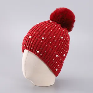 Detail der roten Strickmütze mit Fleecefutter, Perlen, Kristallen und großem Kunstfellbommel