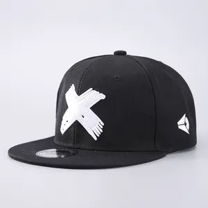 Detail of black snapback hat featuring white X embroidery and silver sport cap sticker