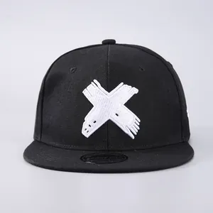 Detailed view of white X embroidery on high-quality black cotton flat brim snapback cap