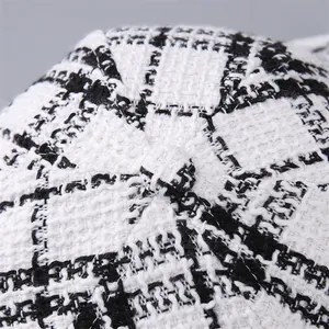 Close-up of black and white houndstooth tweed texture and top button on a baseball cap