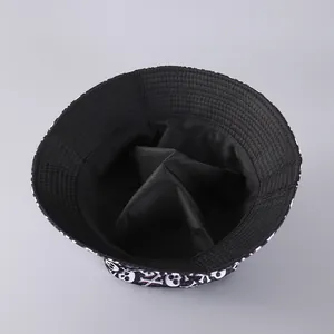 Flat lay detail of a black canvas bucket hat featuring white skull and crossbones print
