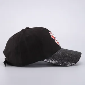 Detalle de gorra de béisbol con lentejuelas plateadas en visera y bordado de dibujos