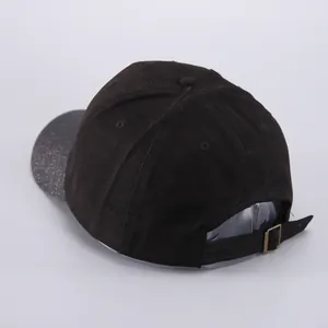 Detalle de la gorra de béisbol negra con visera brillante y hebilla metálica ajustable