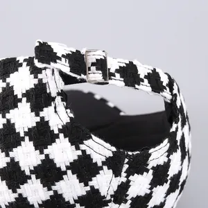 Detail showing houndstooth baseball cap with adjustable silver metal buckle and tweed fabric
