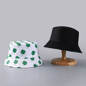 Detail of green clover print and plain black reversible bucket hats on wooden stand