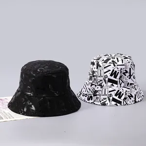 Detail von Fischerhüten aus Baumwolle mit Zeitungs-Buchstabendruck in Schwarz und Weiß