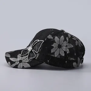 Detail of black lace baseball cap with butterfly rhinestone and gray floral patterns