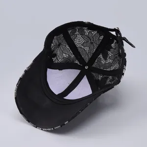 Detail of black floral lace baseball cap showing intricate mesh pattern and inner lining