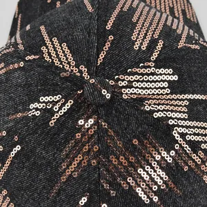 Macro detail of rose gold sequins on black denim baseball cap with geometric pattern