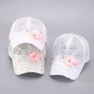 Détail de casquettes en résille à paillettes avec fleurs en rose doré et blanc