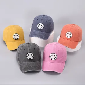 Detail of multi-color washed cotton baseball caps with smiley face patch on display stands