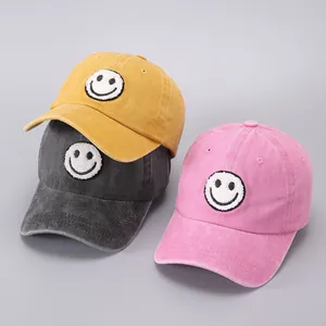 Detailed macro view of vintage washed cotton baseball caps with embroidered smiley face patches