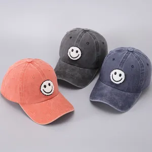 Detailed view of washed cotton baseball caps with embroidered smiley faces in three colors