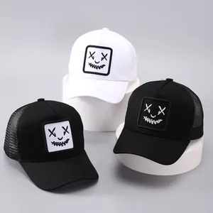 Détail de casquettes trucker avec visage drôle, filet respirant et écusson brodé