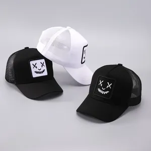Détail de la broderie visage drôle sur les casquettes trucker en noir et blanc