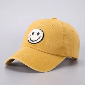 Close-up of mustard yellow cotton baseball cap with embroidered smiley face patch detail