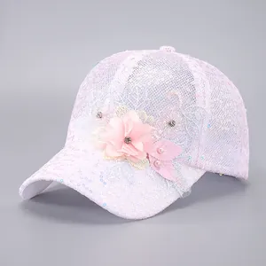 Détail d'une casquette en dentelle rose avec paillettes et décorations florales 3D