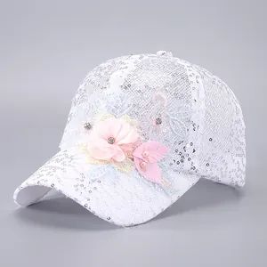 Détail d'une casquette en dentelle blanche avec paillettes argentées et fleurs en 3D