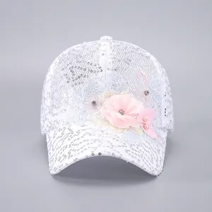 Détail de la casquette blanche en dentelle à paillettes avec fleurs 3D et perles