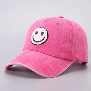 Detailed close-up of pink washed cotton baseball cap with fuzzy smiley face patch