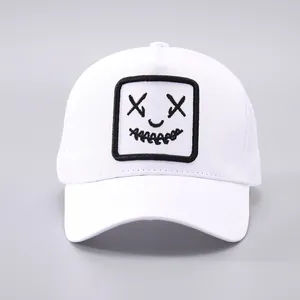 Détail d'une casquette trucker blanche avec un patch brodé d'un visage souriant artistique