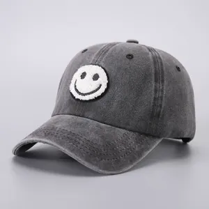 Close-up of charcoal wash cotton baseball cap featuring a white smiley face patch embroidery
