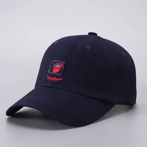 Close-up of navy blue cotton baseball cap with red bucket embroidery and curved brim stitching