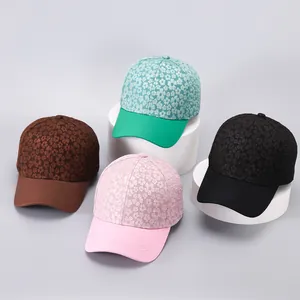 Floral patterned baseball caps in green, brown, pink, and black on display stands