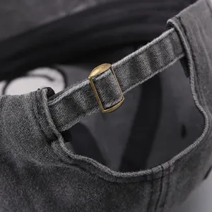 Detail of adjustable metal bronze buckle on washed cotton denim baseball cap back