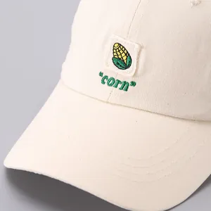 Close-up of corn patch embroidery and texture on cream cotton canvas baseball cap