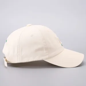 Side view of cream cotton baseball cap with green embroidery and distressed details
