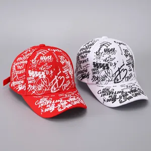 Detail view of red and white baseball caps featuring graffiti prints and curved brims